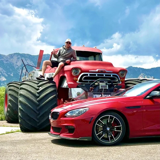 Simon, founder of Platinum Wheels and Tires, with a red BMW M6 and an oversized King Kong monster truck in Colorado